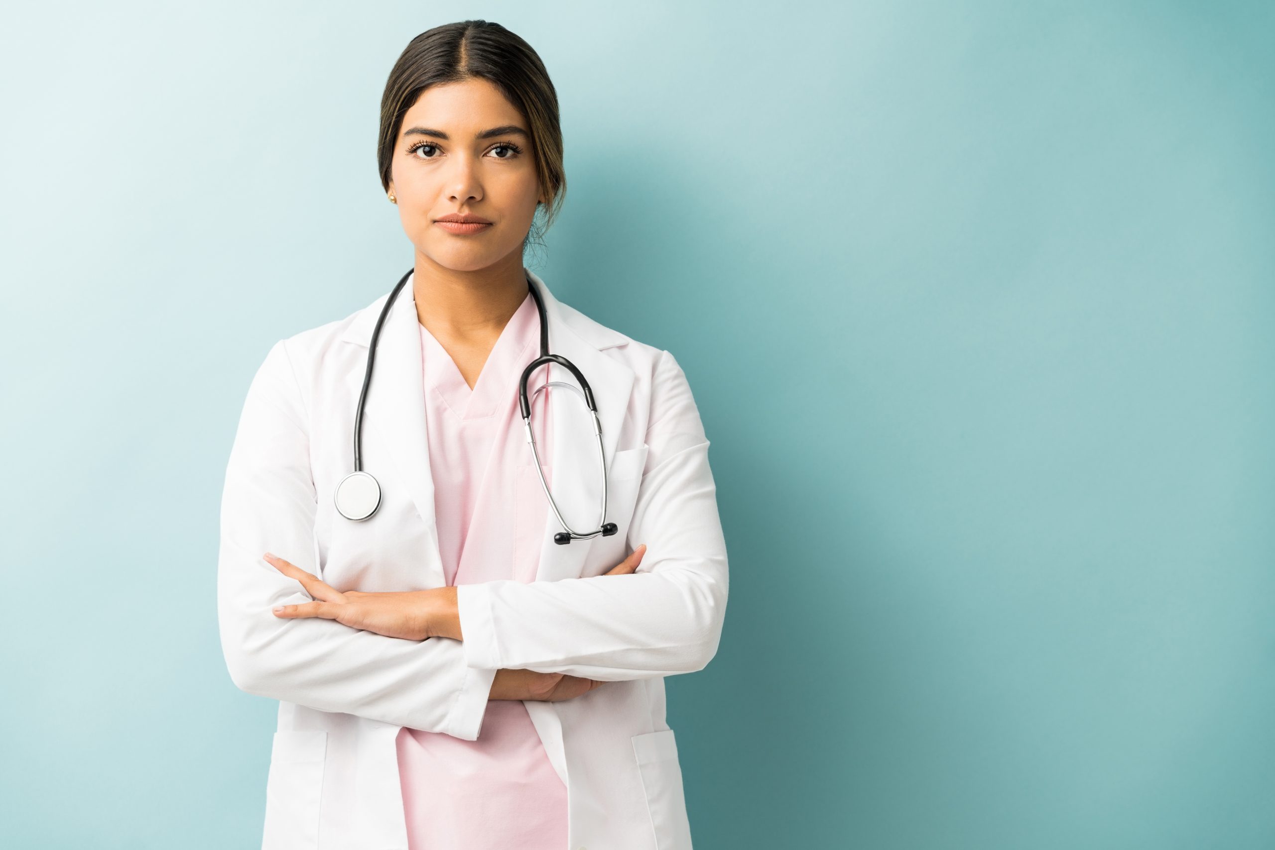 attractive medical professional uniform standing with arms crossed against isolated background scaled
